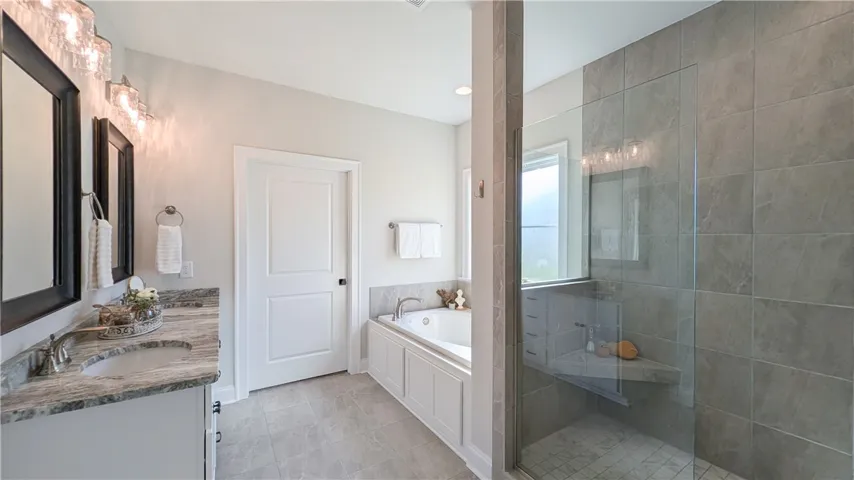 Primary bathroom with gorgeous frameless glass shower, soaking tub, dual sinks, water closet, and enormous walk-in closet!