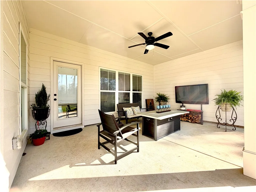 An inviting covered patio features a ceiling fan, offering a comfortable outdoor living space.