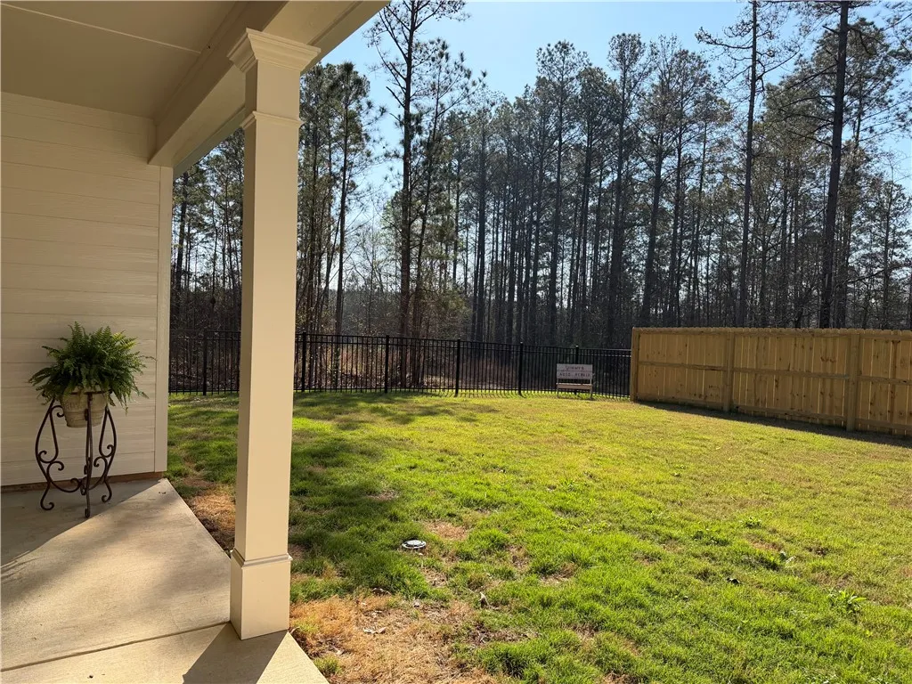 A verdant lawn extends to a mix of wood and iron fencing, backed by a serene forest.