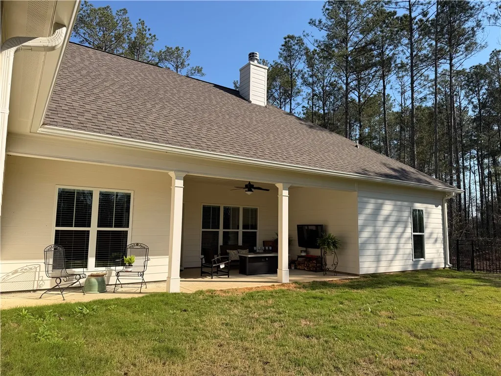 A spacious covered patio offers ample room for relaxation and entertaining, overlooking a verdant backyard.