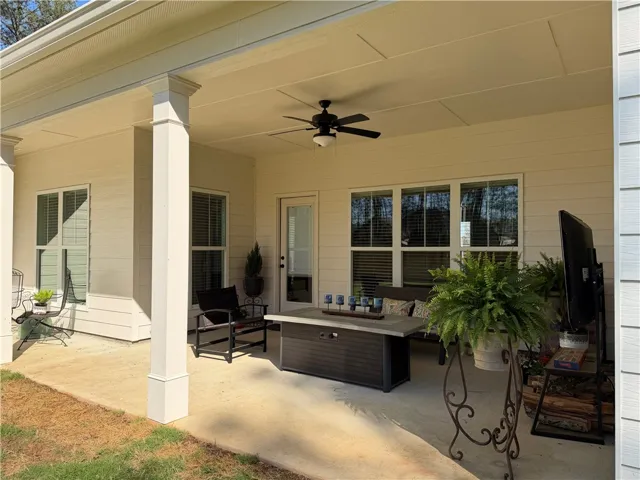 An inviting covered patio, perfect for relaxing or entertaining, features a cooling ceiling fan and ample space.