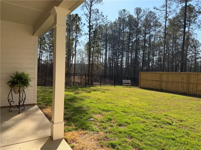 A verdant lawn extends to a mix of wood and iron fencing, backed by a serene forest.
