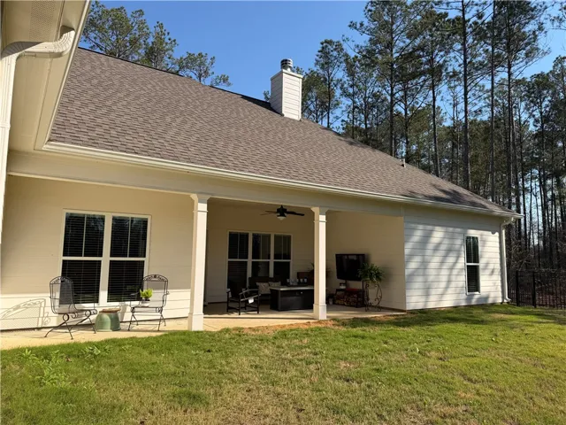 A spacious covered patio offers ample room for relaxation and entertaining, overlooking a verdant backyard.
