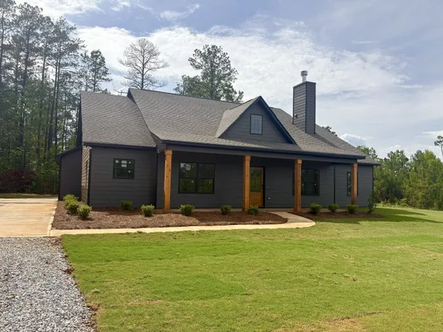 Crafted with dark siding and timber columns, this home presents a modern rustic facade.