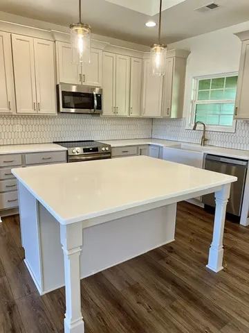 A well-appointed kitchen features stainless steel appliances, gleaming countertops, and rich wood flooring.