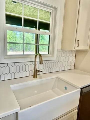 A well-appointed kitchen features a deep farmhouse sink, sleek countertops, and a striking tile backsplash.