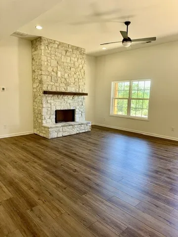A grand stone fireplace anchors this living space with its warm wood flooring and outdoor views.