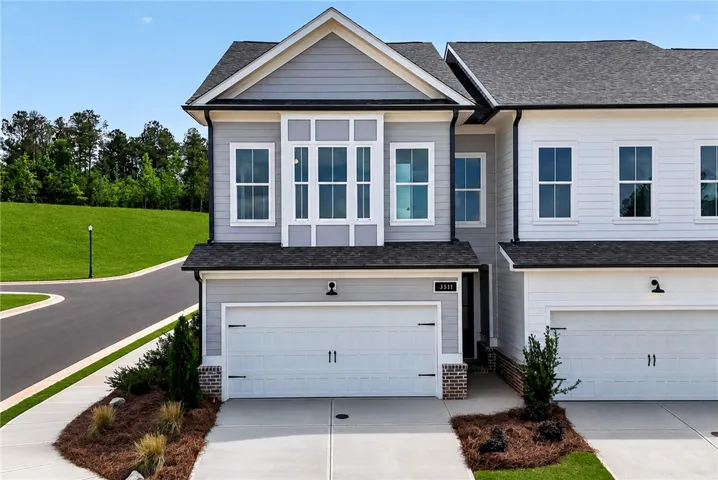 A striking gray and white facade boasts a practical attached garage and manicured landscaping.