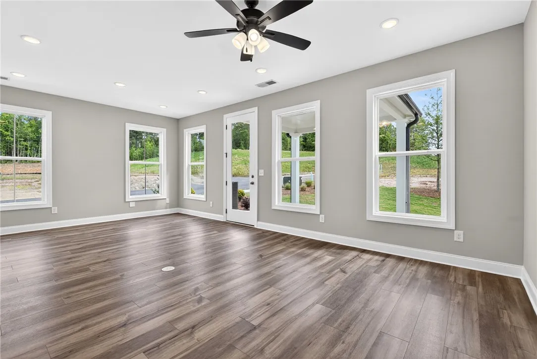 A versatile living space with light wood flooring and multiple windows framing scenic views.