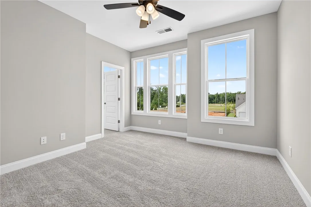 Well-lit living area with plush carpeting and expansive windows capturing serene views.