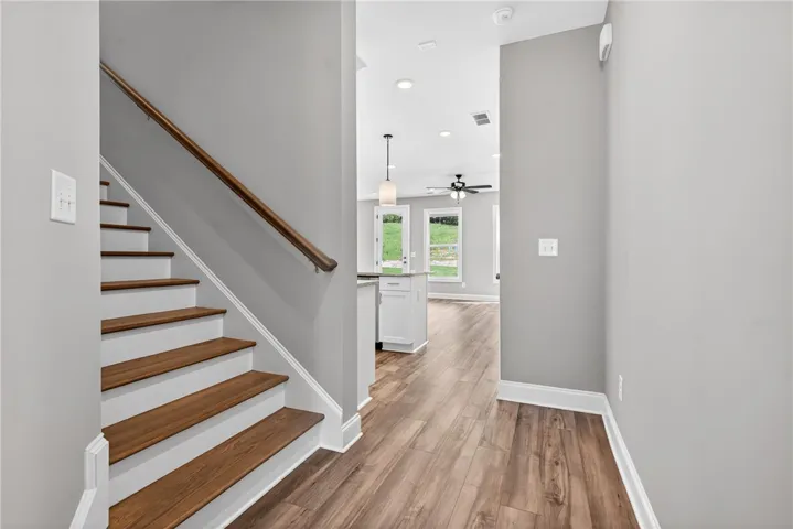 A striking entry features rich hardwood stairs, leading into an airy open-concept living space with abundant light.