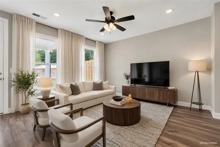 Natural light floods this living area, highlighting warm wood flooring and a modern ceiling fan.