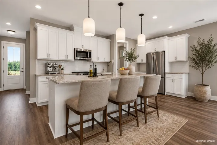 An inviting kitchen with pristine white cabinetry, granite countertops, and modern pendant lighting over the central island.