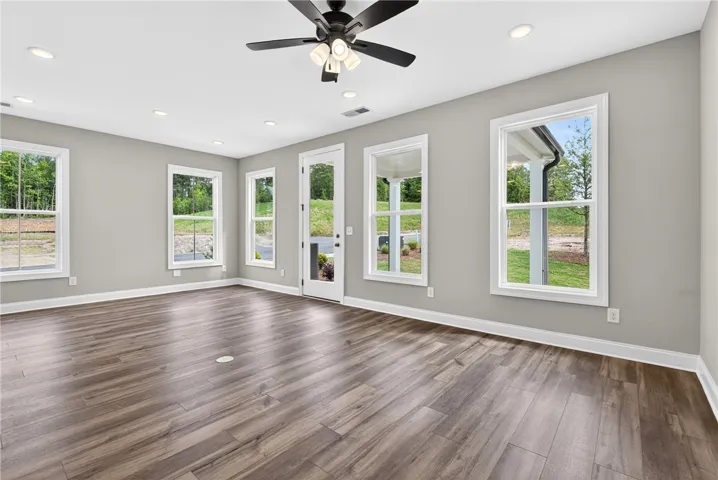 A versatile living space with light wood flooring and multiple windows framing scenic views.