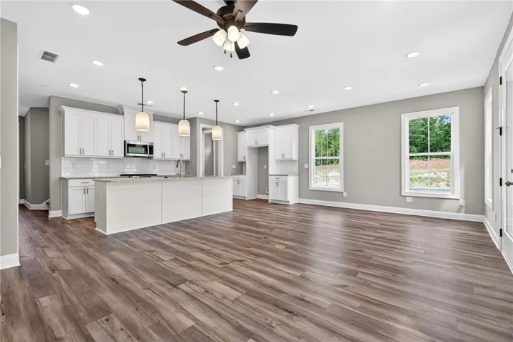 A pristine open-concept kitchen and living area features rich hardwood flooring and abundant natural illumination.