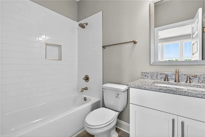 A refined bathroom featuring a clean bathtub and a vanity with a sophisticated granite counter.