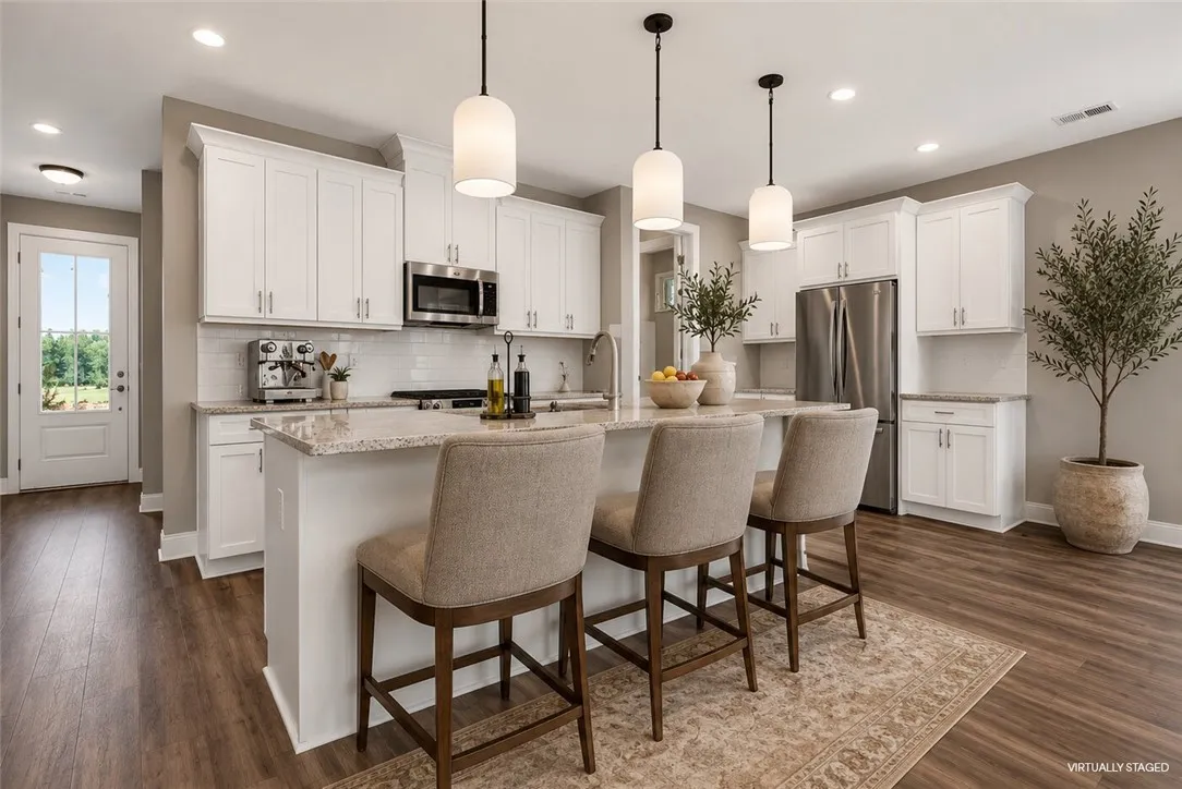 Granite counters and stainless steel appliances adorn this bright, open-concept kitchen.