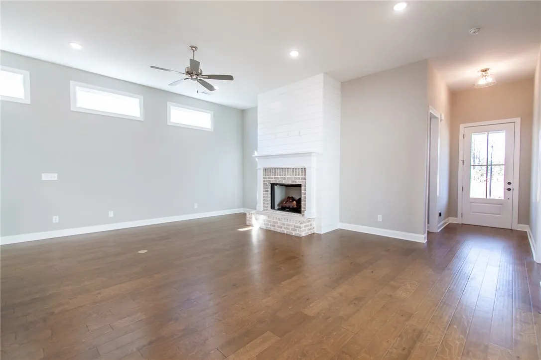 This living area features a warm fireplace and rich hardwood flooring, perfect for comfortable gatherings. Photos are not of subject property. Photos are of the same floorplan of a completed home.