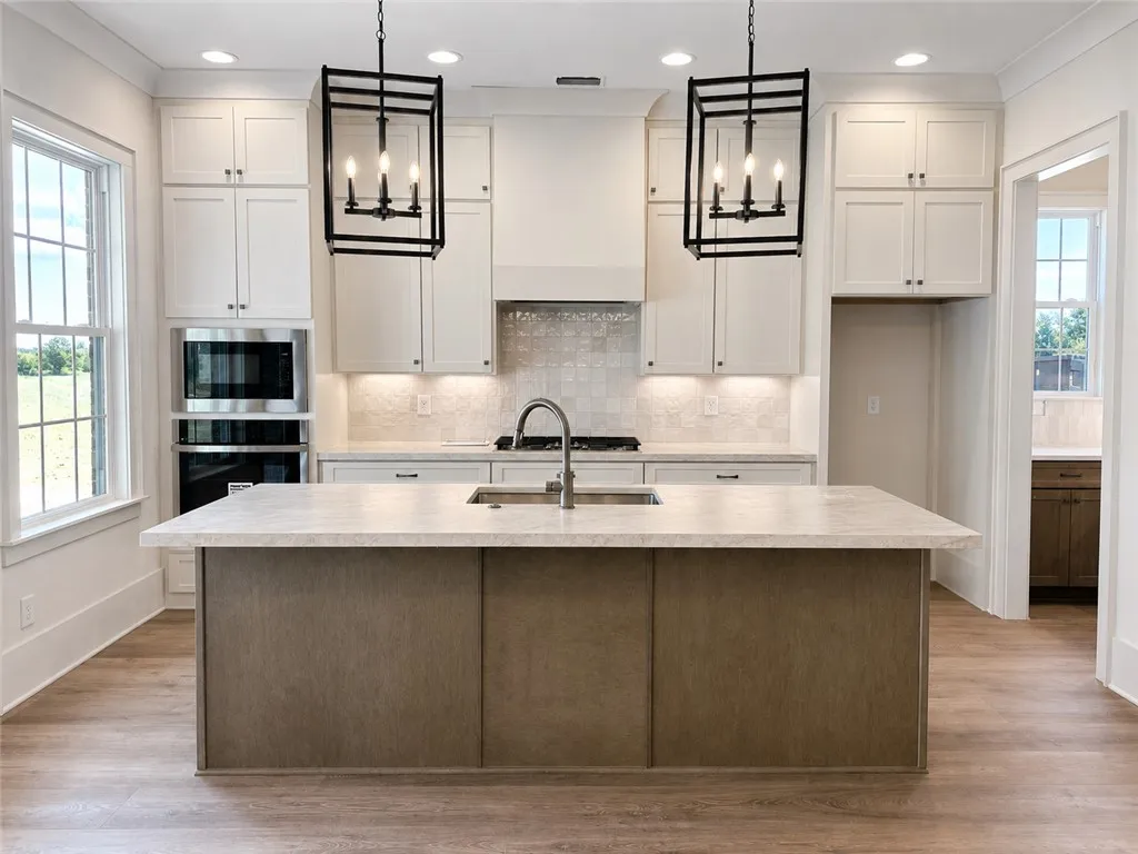 Rich LVP floors support a spacious prep island beneath custom cabinetry and recessed lighting.