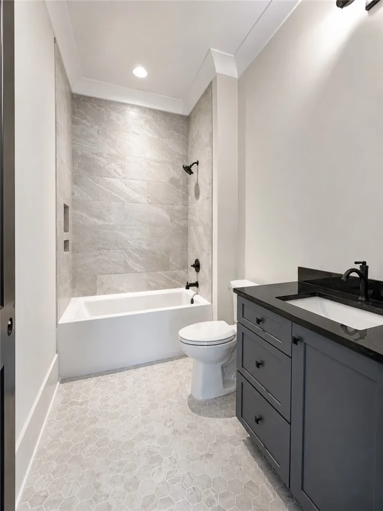 A modern tiled shower and tub combination stands next to a dark vanity.