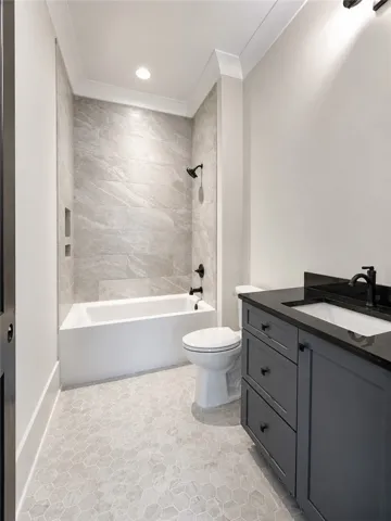 A modern tiled shower and tub combination stands next to a dark vanity.
