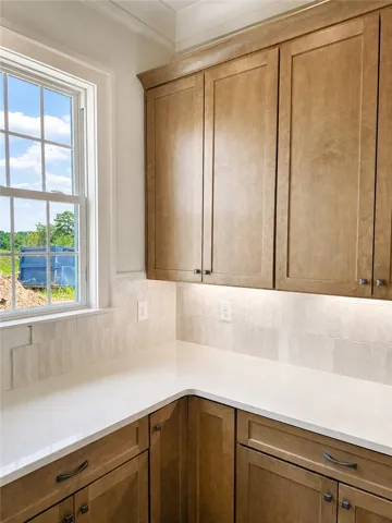 cabinetry pairs with solid countertops alongside a window framing outdoor views.
