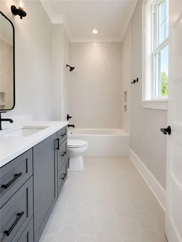 Crisp white crown molding accents this bright bathroom, featuring a deep soaking tub and sleek vanity with modern hardware.