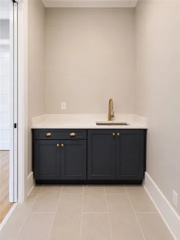 A refined wet bar area features deep-toned cabinetry and a sleek gold-finished faucet, creating a convenient beverage station.