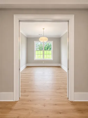 A quiet space for contemplation or work, featuring light wood flooring and a large window framing verdant views.