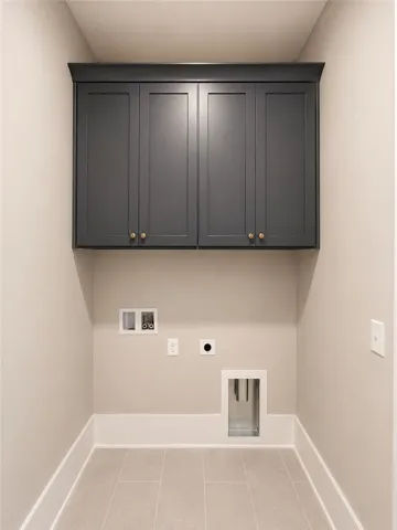 Functional laundry room featuring elegant cabinetry and durable tile flooring for everyday ease.