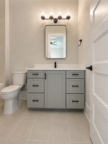 A well-appointed bathroom features a sleek vanity, modern mirror, and light-toned tile flooring.