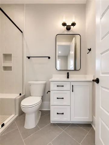 A well-appointed bathroom features a sleek vanity, modern fixtures, and a glass-enclosed shower with tiled walls.