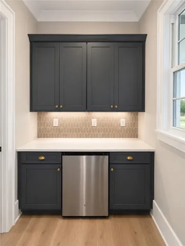 A well-appointed wet bar with sleek cabinetry, elegant backsplash, and under-cabinet lighting offers convenient entertaining.