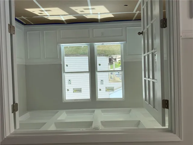 This newly constructed room features elegant wall paneling and ample natural light through its windows.