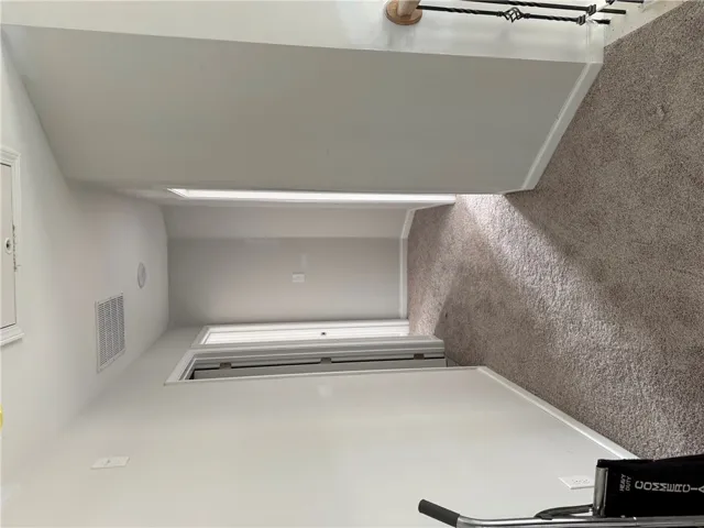This spacious hallway offers comfortable carpeting and leads to various rooms within the home.