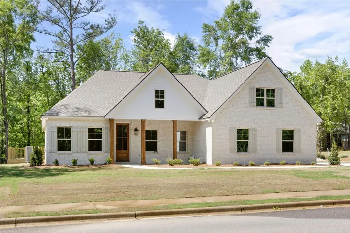 This inviting home features a classic brick exterior, charming shutters, and a welcoming covered porch.