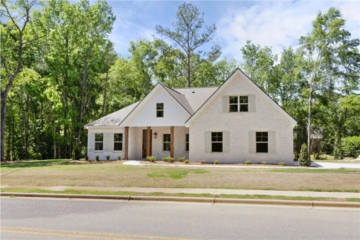 This charming home offers a welcoming facade with attractive window shutters and lush surroundings.