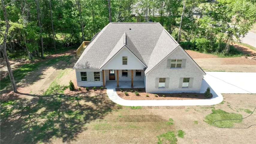 This newly constructed home showcases a welcoming front porch and an expansive driveway.