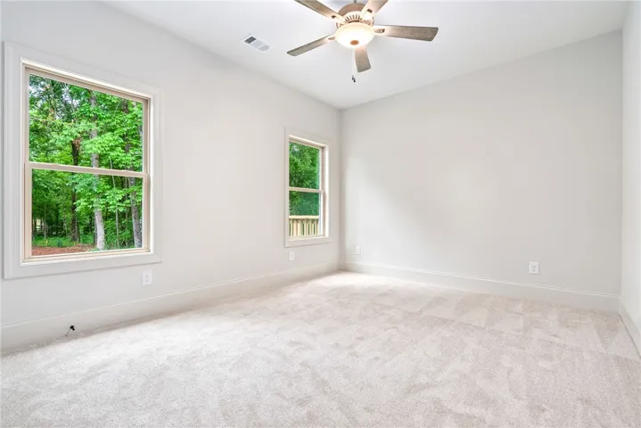 This spacious room features ample natural light and plush carpeting, offering a comfortable atmosphere.