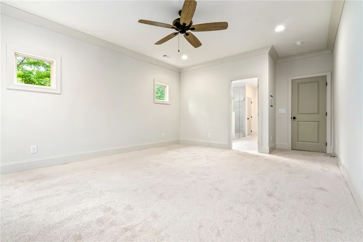 This airy bedroom features plush carpeting and abundant natural light, creating a serene personal retreat.