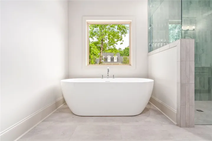 Relax in this tranquil bathroom, featuring a freestanding tub and a spacious glass-enclosed shower.