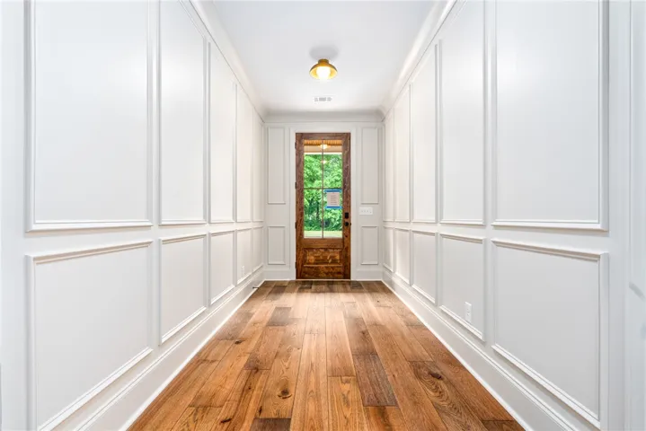 Step inside this inviting hallway, featuring polished hardwood and elegant wainscoting.