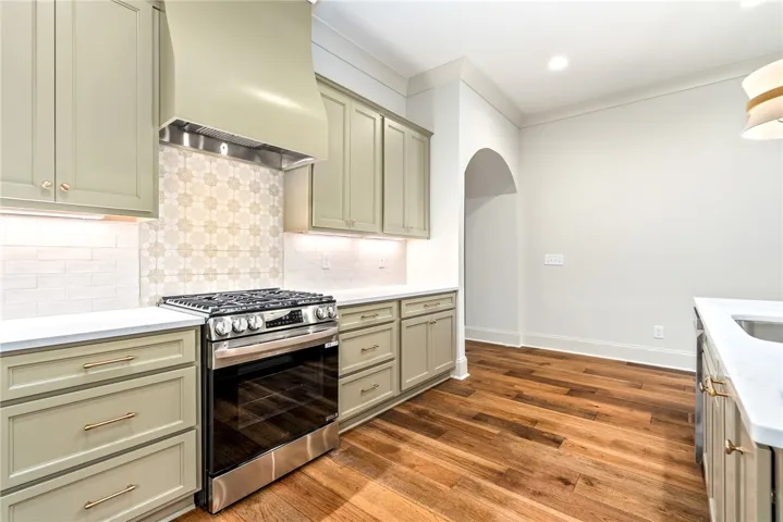 This modern kitchen features warm wood flooring and sleek, functional appliances.