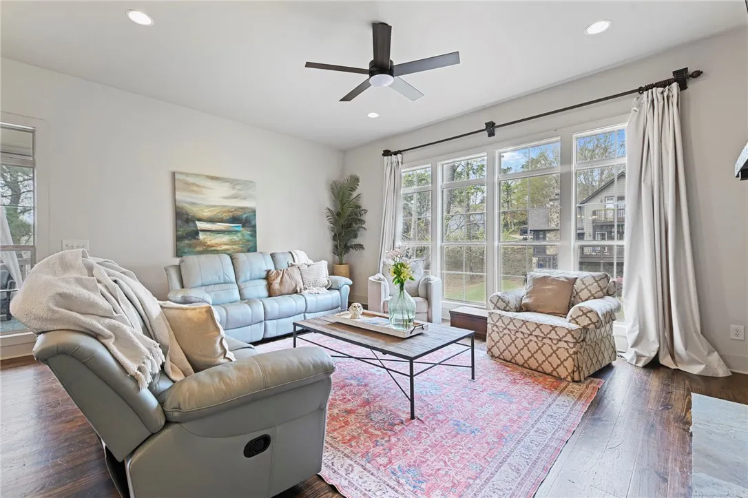 A naturally illuminated living room features gleaming hardwood floors and large windows overlooking the surrounding landscape.
