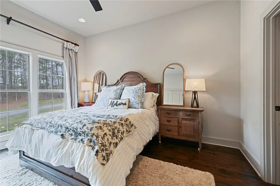 Natural light floods this charming bedroom featuring polished hardwood flooring and serene views.