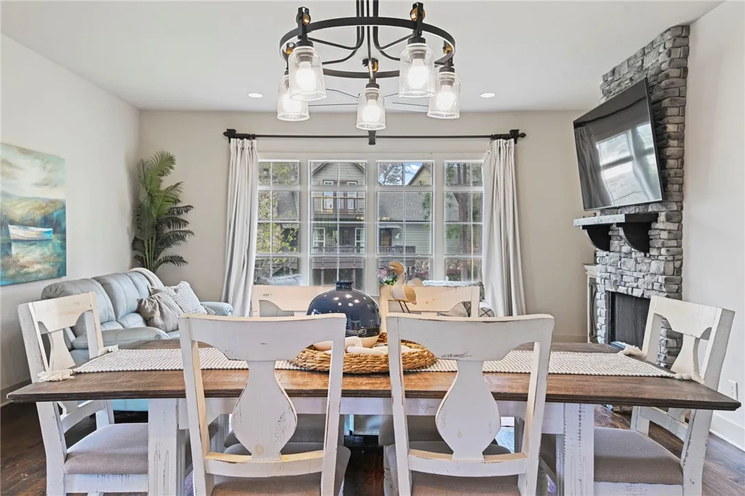 A charming dining space with a stone fireplace and abundant natural light from large windows.