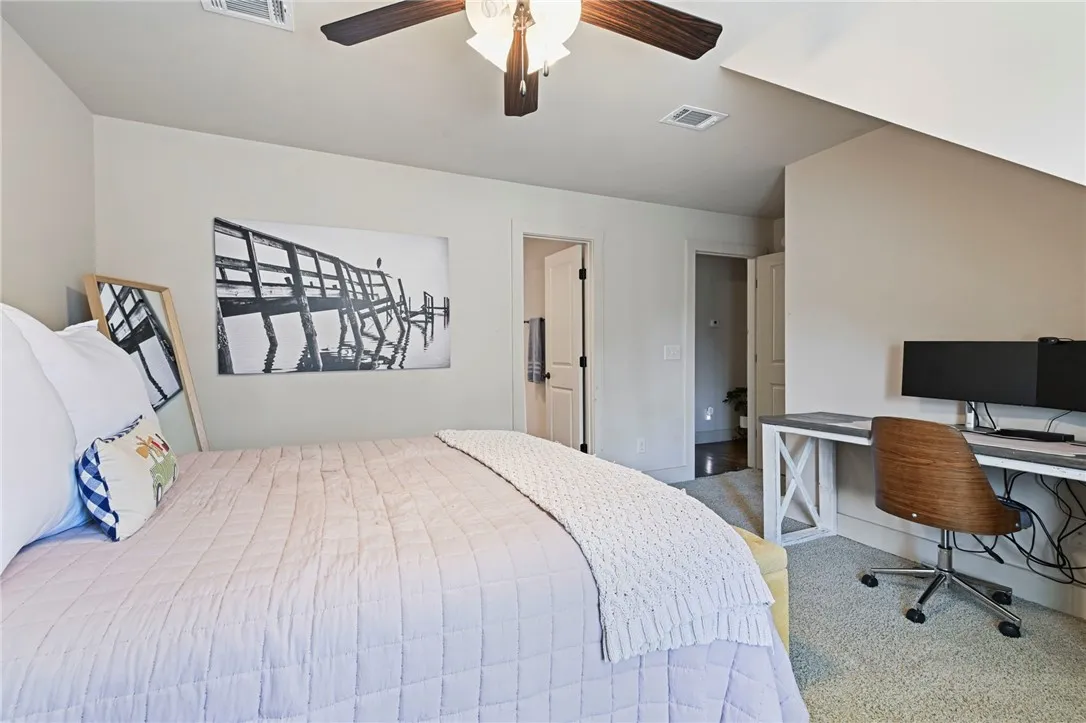 A comfortable bedroom with a slanted ceiling features a ceiling fan for optimal airflow.