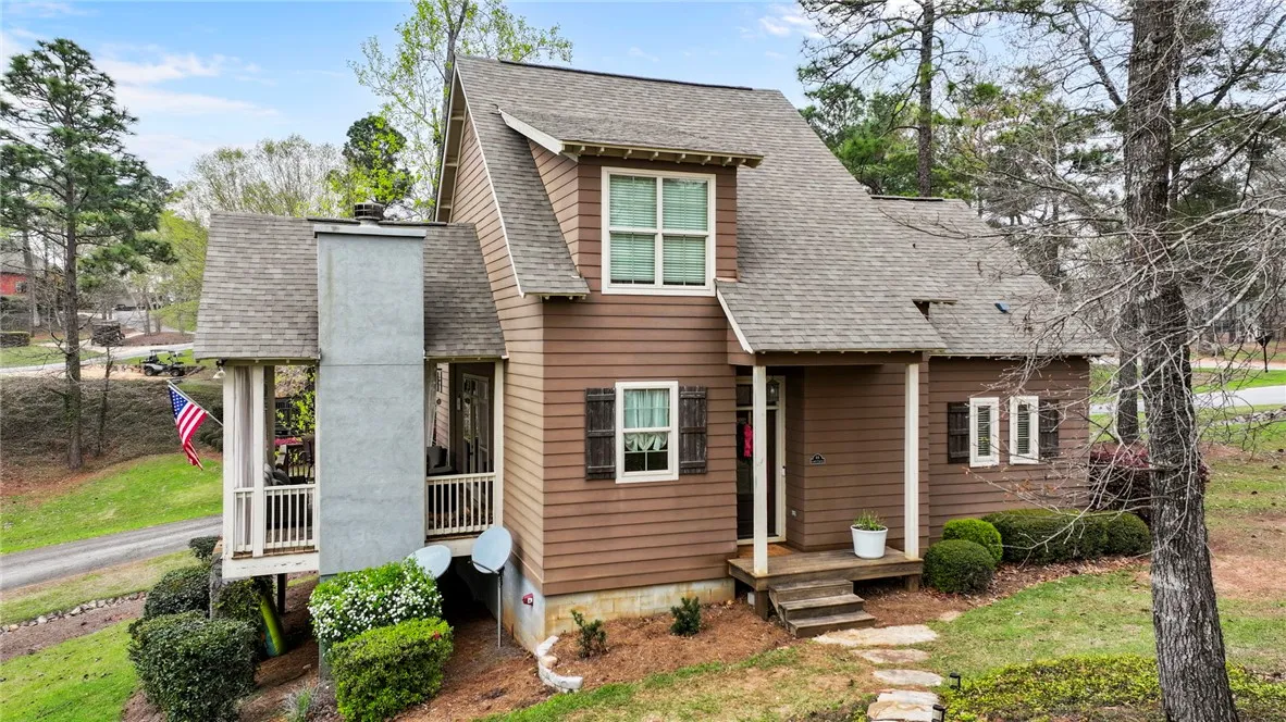 A charming brown-sided home boasts a distinctive roofline and inviting front porch steps.