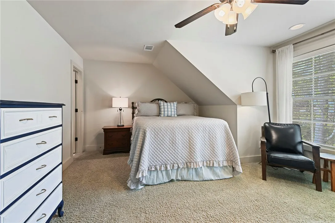 A cozy bedroom with textured carpet and an inviting window offers serene repose.