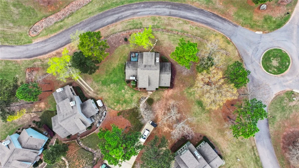An aerial perspective reveals a secluded residence nestled amongst a verdant landscape with a winding driveway and nearby homes.